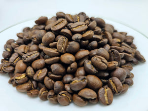 Whole roasted coffee beans on a white plate