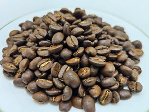 Whole roasted coffee beans on a white plate