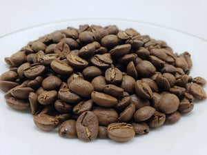 Roasted coffee beans on a white plate, representing the organic and ethically sourced coffee product.