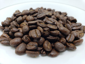 A pile of roasted coffee beans on a white plate.