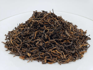  Loose-leaf dark tea piled on a white plate.