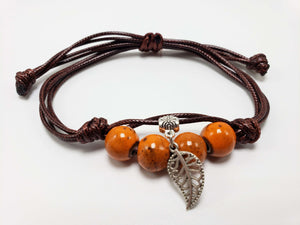Handmade brown cord bracelet with orange beads and silver leaf charm