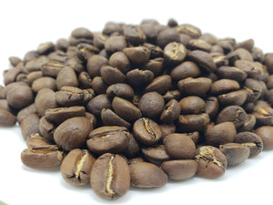 A pile of whole bean coffee in a light to medium roast, indicating a smooth and possibly sweet flavor profile.
