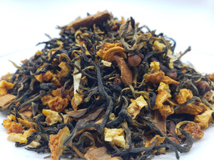 A close-up of Winter Sunrise Loose-Leaf Tea with visible black tea leaves, orange peel, and spices.